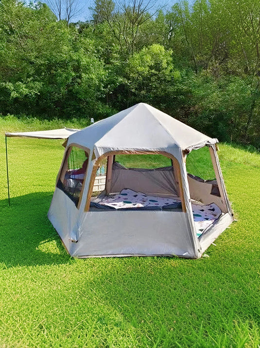 Outdoor tent set up on grass with trees in the background