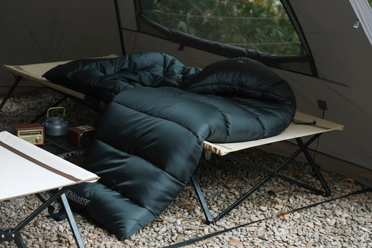 A dark green sleeping bag on a camping chair outdoors.