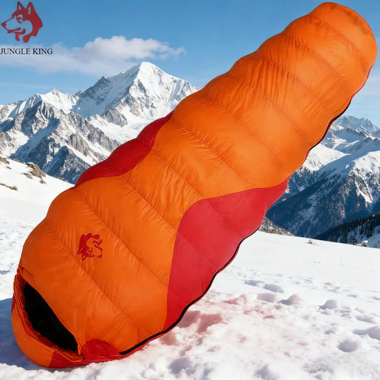 Orange and red sleeping bag on a snowy mountain with 'Jungle King' branding.