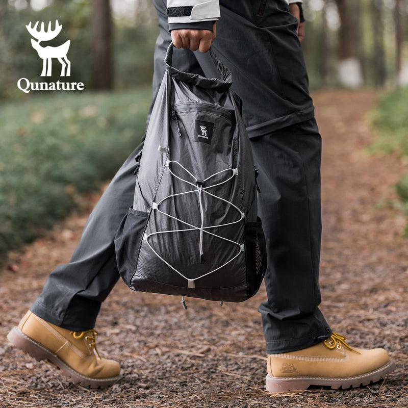 Load image into Gallery viewer, Person holding a black backpack with Qunature logo in a forest setting

