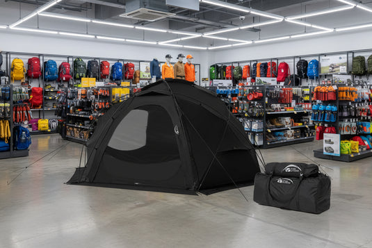 Black hemispherical camping tent with carrying bag on a white background