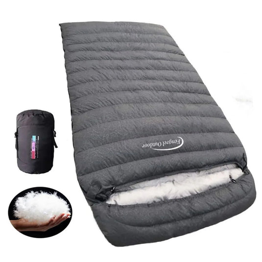 Gray sleeping bag with white interior and black compression sack on a white background