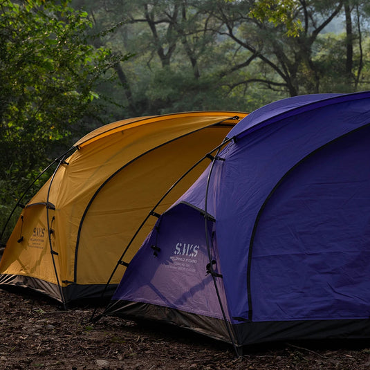 Two tents, one yellow and one blue, set up in a forest with 'WELLHIKE minimalism' branding.