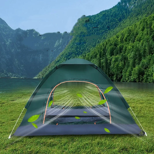 Green camping tent set up in a grassy area with mountains and water in the background