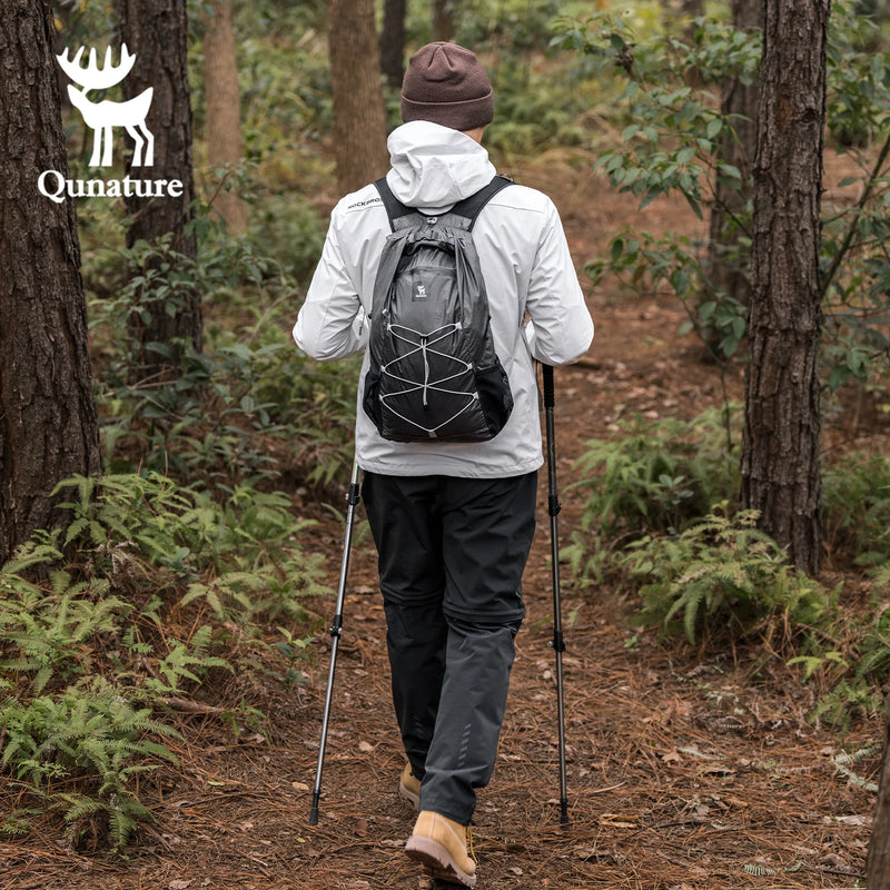 Load image into Gallery viewer, Person hiking in a forest with a Qunature backpack and poles, brand logo visible.
