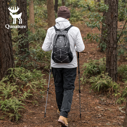 Person hiking in a forest with a Qunature backpack and poles, brand logo visible.