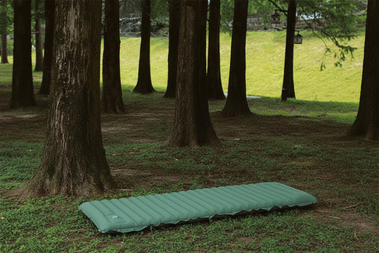 A green inflatable mattress in a forest setting
