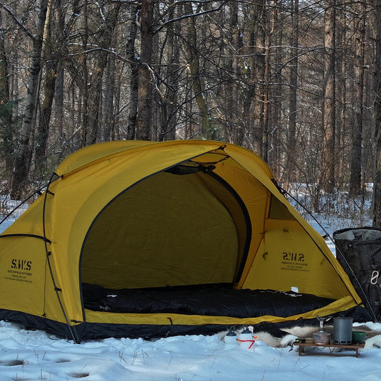 Yellow tent set up in a snowy forest with 'WELLHIKE minimalism' branding.