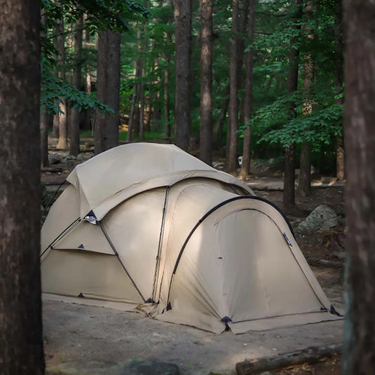 Beige tent set up in a forest setting
