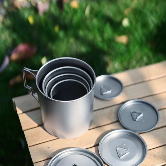 Set of metal mugs with lids on a wooden surface outdoors