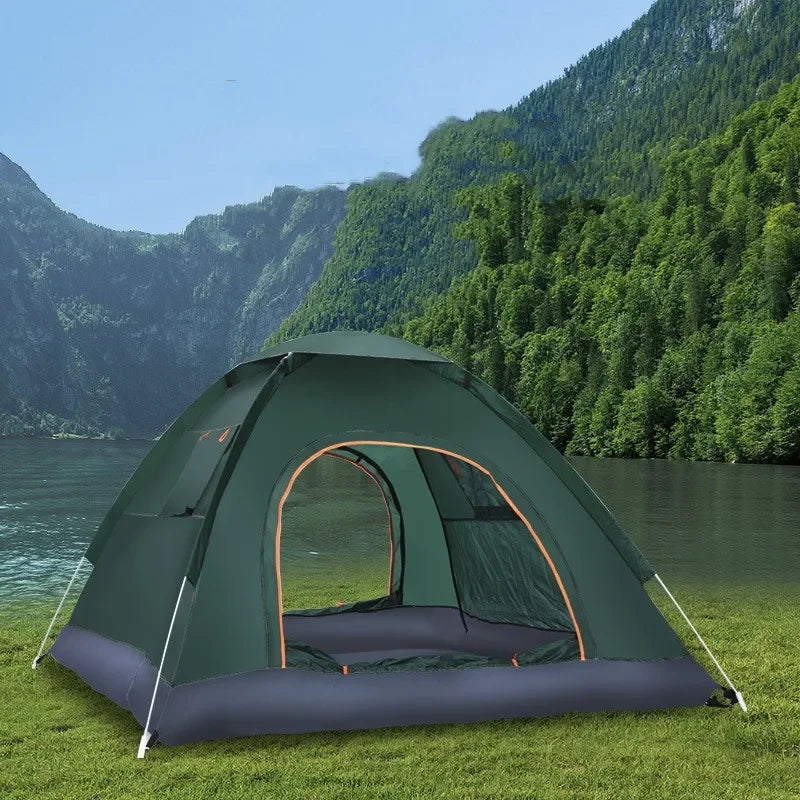 Load image into Gallery viewer, Green camping tent with orange accents set up on grass near a lake and mountains.
