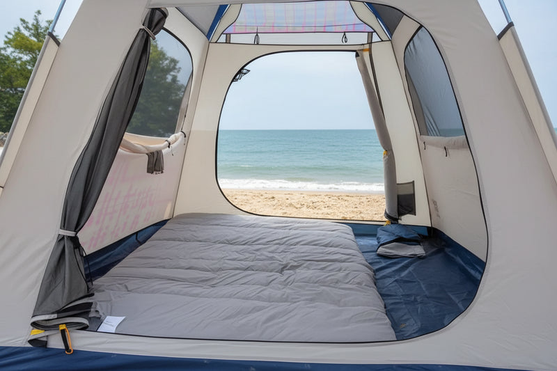 Load image into Gallery viewer, Person using a camping mattress pad with an orange blanket in a vehicle by the sea.
