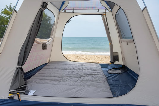 Person using a camping mattress pad with an orange blanket in a vehicle by the sea.